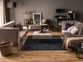 Elegancki salon z szarymi ścianami, które podkreślają ciepłe drewno podłogi i mebli. Idealne kolory ścian do salonu dla przytulnej atmosfery.