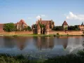 Potężny zamek z czerwonej cegły, największy zamek na świecie, odbija się w spokojnej wodzie.