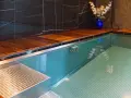 Luksusowy basen w domu z drewnianym tarasem i niebieską wazą z kwiatami.