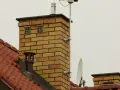 Na dachu ceglanego komina widać dwa otwory wentylacyjne, które mogą służyć jako odpowietrzenie kanalizacji. Obok znajduje się antena satelitarna.