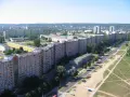 Długi, falisty budynek mieszkalny, znany jako falowiec gdańsk, rozciąga się na tle zieleni i innych bloków.