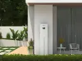 Nowoczesny magazyn energii 5 kW na ile wystarczy? Urządzenie SolaX stoi przy domu z ogrodem, oferując niezależność energetyczną.
