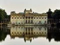 Pałac na Wyspie w Łazienkach Królewskich, arcydzieło **neoklasycyzmu**, odbija się w spokojnej tafli wody.