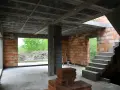 Budowa domu w stanie surowym. Widoczne stropy gęstożebrowe, ściany z cegły, schody betonowe i materiały budowlane.