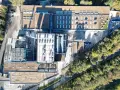 Widok z lotu ptaka na kompleks budynków z zielonym dachem płaskim, panelami słonecznymi i infrastrukturą przemysłową.