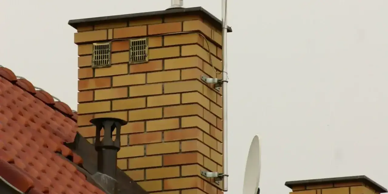 Na dachu ceglanego komina widać dwa otwory wentylacyjne, które mogą służyć jako odpowietrzenie kanalizacji. Obok znajduje się antena satelitarna.