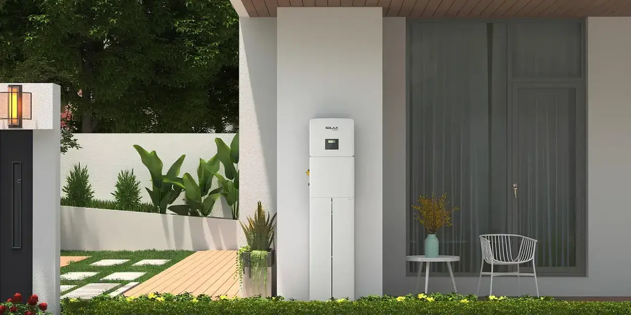 Nowoczesny magazyn energii 5 kW na ile wystarczy? Urządzenie SolaX stoi przy domu z ogrodem, oferując niezależność energetyczną.