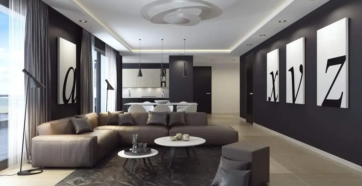Nowoczesny salon z narożną kanapą w kolorze brązowym, czarnymi akcentami i obrazami liter. Ściany w odcieniu **ral 9005** tworzą eleganckie tło.