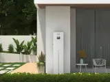Nowoczesny magazyn energii 5 kW na ile wystarczy? Urządzenie SolaX stoi przy domu z ogrodem, oferując niezależność energetyczną.