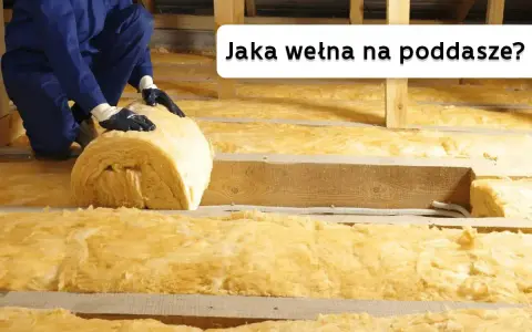 Ocieplanie poddasza wełną mineralną. Pracownik układa rolkę izolacji między drewnianymi belkami.