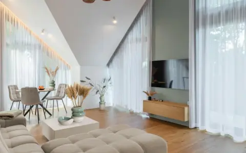 Przytulny salon z sofą w kolorze kremowym, stołem i krzesłami, ozdobiony trawami pampasowymi.
