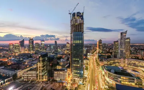 Varso Tower w budowie, otoczony innymi wieżowcami Warszawy o zmierzchu.