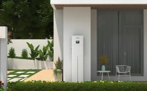 Nowoczesny magazyn energii 5 kW na ile wystarczy? Urządzenie SolaX stoi przy domu z ogrodem, oferując niezależność energetyczną.