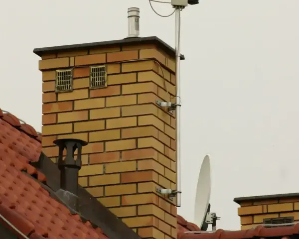 Na dachu ceglanego komina widać dwa otwory wentylacyjne, które mogą służyć jako odpowietrzenie kanalizacji. Obok znajduje się antena satelitarna.