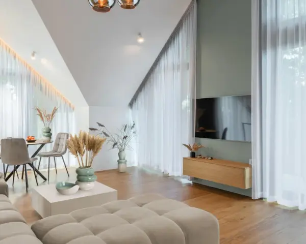 Przytulny salon z sofą w kolorze kremowym, stołem i krzesłami, ozdobiony trawami pampasowymi.