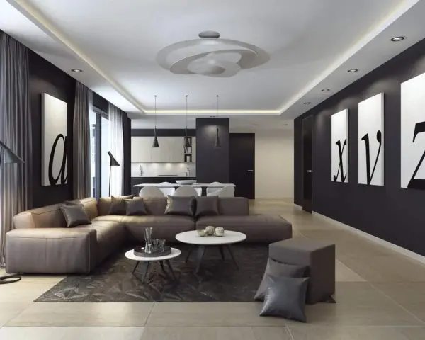 Nowoczesny salon z narożną kanapą w kolorze brązowym, czarnymi akcentami i obrazami liter. Ściany w odcieniu **ral 9005** tworzą eleganckie tło.