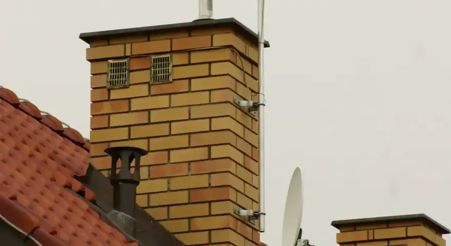 Na dachu ceglanego komina widać dwa otwory wentylacyjne, które mogą służyć jako odpowietrzenie kanalizacji. Obok znajduje się antena satelitarna.