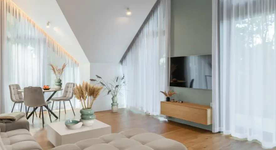 Przytulny salon z sofą w kolorze kremowym, stołem i krzesłami, ozdobiony trawami pampasowymi.