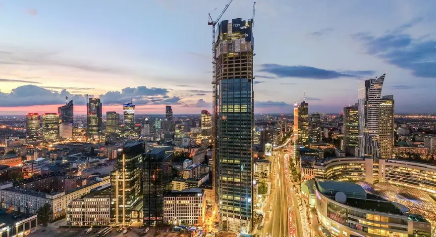 Varso Tower w budowie, otoczony innymi wieżowcami Warszawy o zmierzchu.