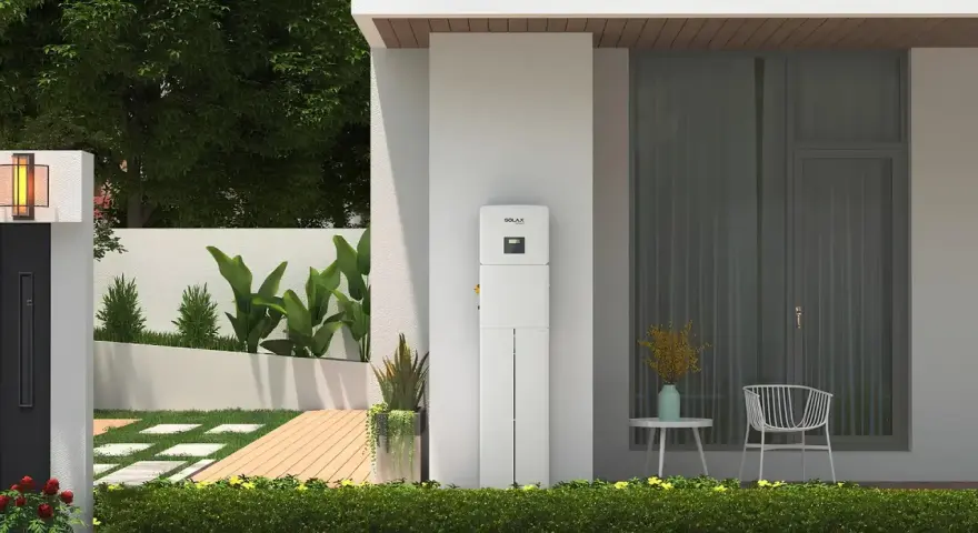 Nowoczesny magazyn energii 5 kW na ile wystarczy? Urządzenie SolaX stoi przy domu z ogrodem, oferując niezależność energetyczną.