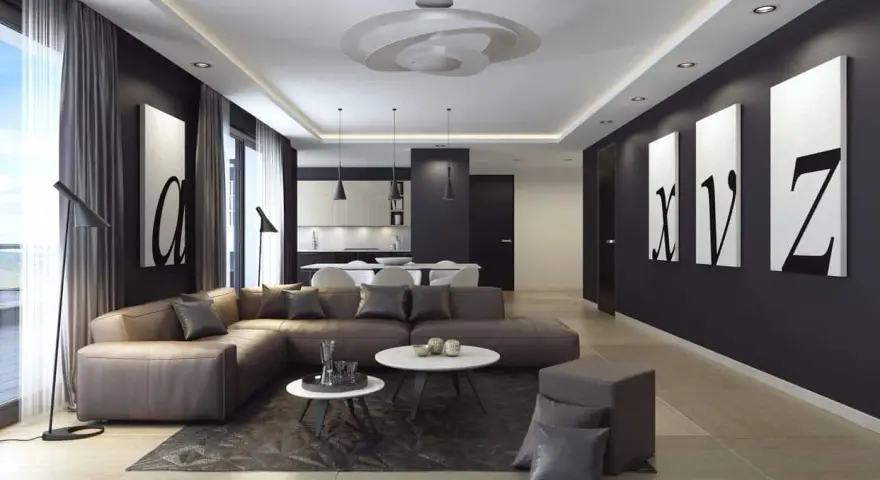 Nowoczesny salon z narożną kanapą w kolorze brązowym, czarnymi akcentami i obrazami liter. Ściany w odcieniu **ral 9005** tworzą eleganckie tło.