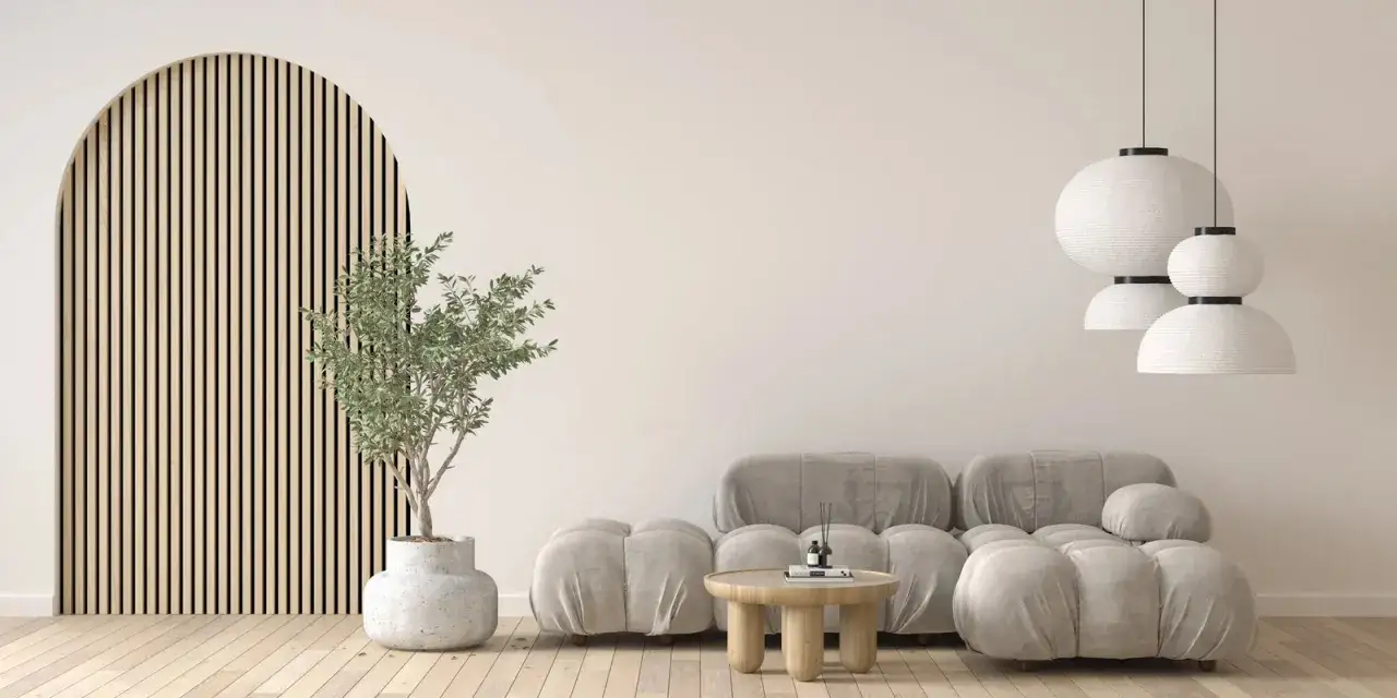 Salon w stylu japandi: łuk z drewnianych listew, szara sofa, okrągły stolik i rośliny.