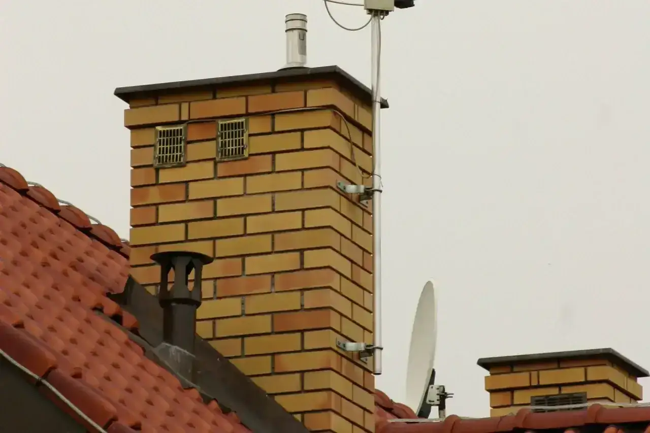 Ceglana kominowa wieża z dwoma kratkami wentylacyjnymi, które mogą służyć jako odpowietrzenie kanalizacji. Na dachu widoczna jest też antena satelitarna.